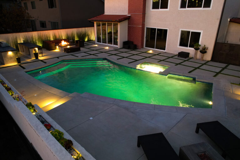 Modern backyard with illuminated swimming pool.