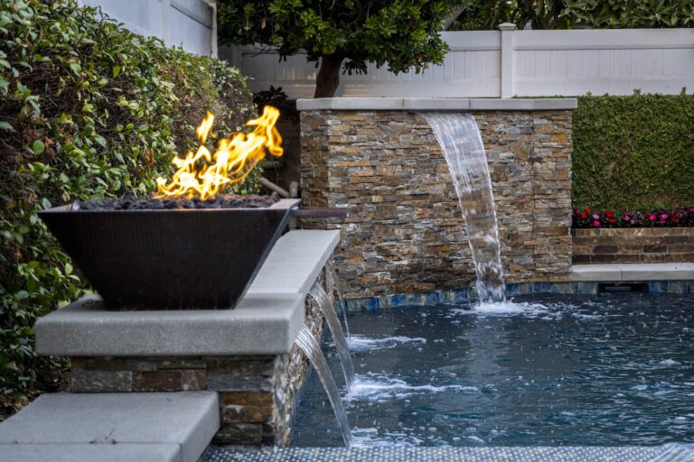 Fire bowl and waterfall by backyard pool.