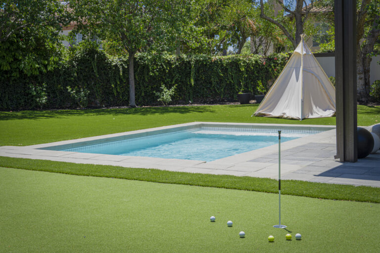 Backyard with pool, golf green, and tent.