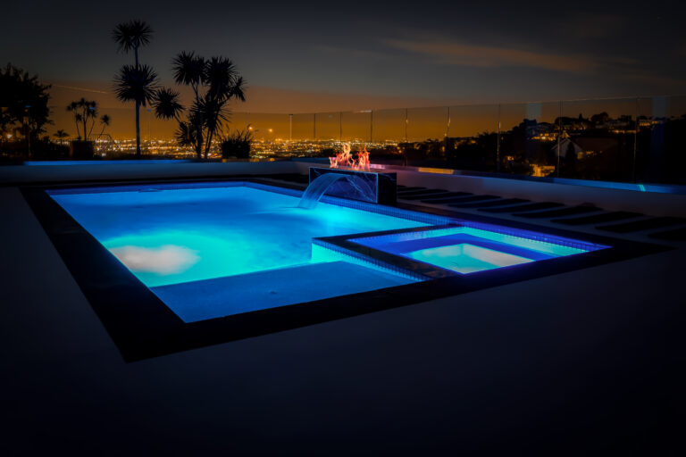 Illuminated pool and cityscape at night.