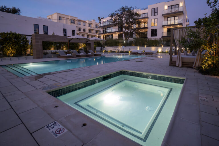 Modern apartment complex with illuminated pool area.